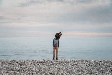 Canvas Print - Traveler woman standing on coast in windy weather