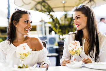 Two beautiful young women smiling and having a fruit salad in a