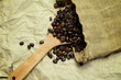 Coffee beans on wooden Spoon in burlap sack on brown paper backg