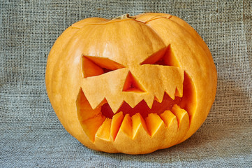 Halloween orange pumpkin on a burlap background in a rustic styl