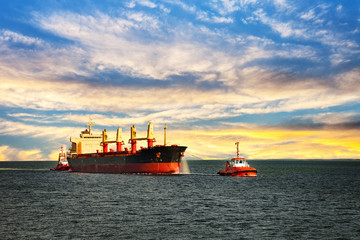 Wall Mural - Tugboats assisting cargo ship sea in the morning.