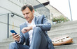 © Westend61 - Businessman sitting on stairs using smart phone