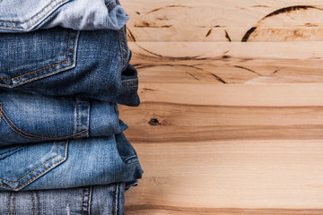 Sticker - fashionable clothes. pile of jeans on a wooden background