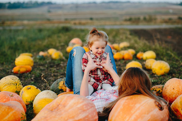 mother and daughter lie between pumpkins