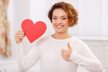 Pleasant girl holding heart