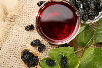 Wall Mural - Glass of refreshing mulberry juice with berries on table close up