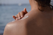 Mujer aplicando crema de proteccion solar en la espalda. 