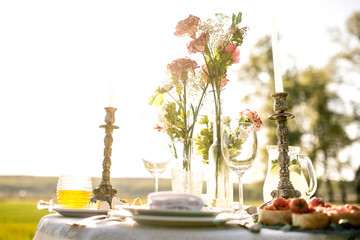 beautifully laid a festive table for two in the garden with flowers and candles