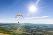 Two paragliders under the rays of a white sun