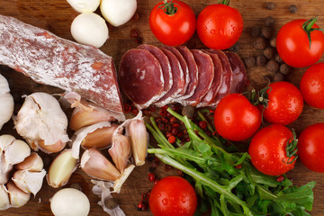 Wall Mural - Salami with cherry tomatoes, ruccola and garlic on a cutting boa