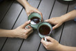 © Mint Images - Hands of man and woman holding coffee cups on table
