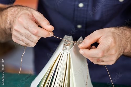 Fotografia, Obraz Midsection Of Male Worker Binding Pages