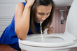 Beautiful adult woman vomiting in toilet