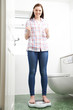 © highwaystarz - Happy Teenage Girl Standing On Bathroom Scales
