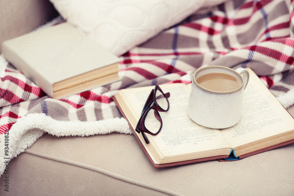 Cup of coffee with book on sofa in living room