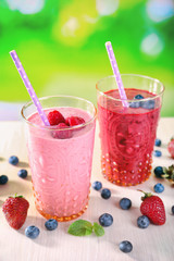 Wall Mural - Glasses of berry smoothie on wooden table on blurred background