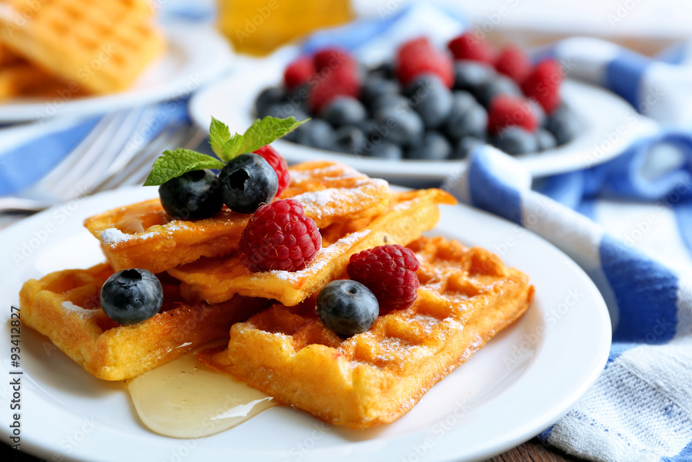 Sweet homemade waffles with forest berries and sauce on table background