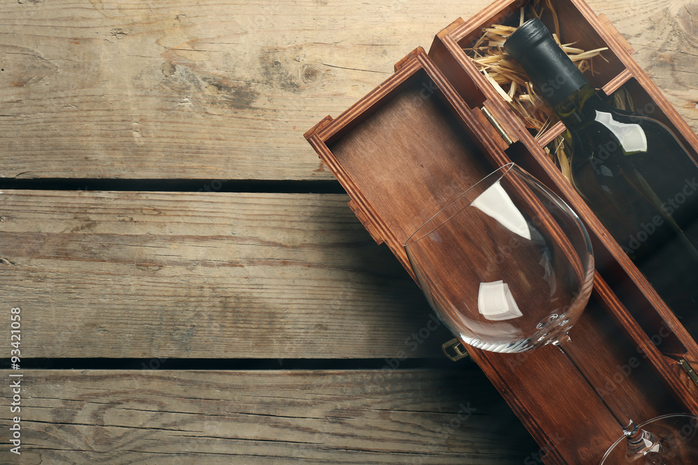 Bottle of wine and empty glass in case on wooden table