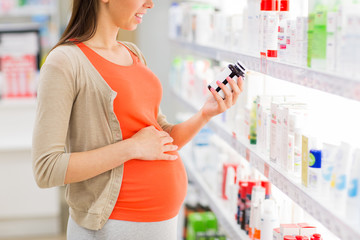 happy pregnant woman with medication at pharmacy