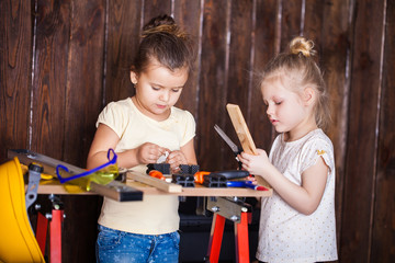 Two little girls making very interesting creations with tools and wood at home