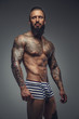 © Fxquadro - Brutal tattooed man in stripes panties.