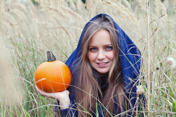 beautiful young woman on an autumn field holding pumpkin