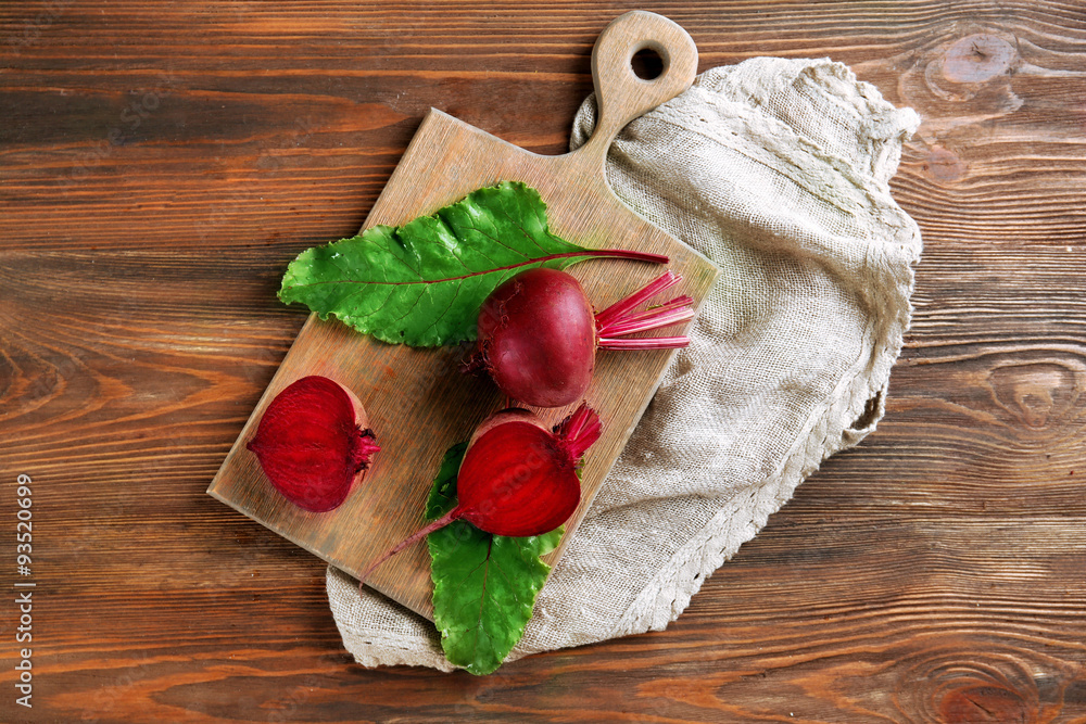 Young beets with leaves on wooden table close up