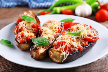 Wall Mural - Dish of eggplant with cherry tomatoes and cheese in white plate on wooden table, closeup