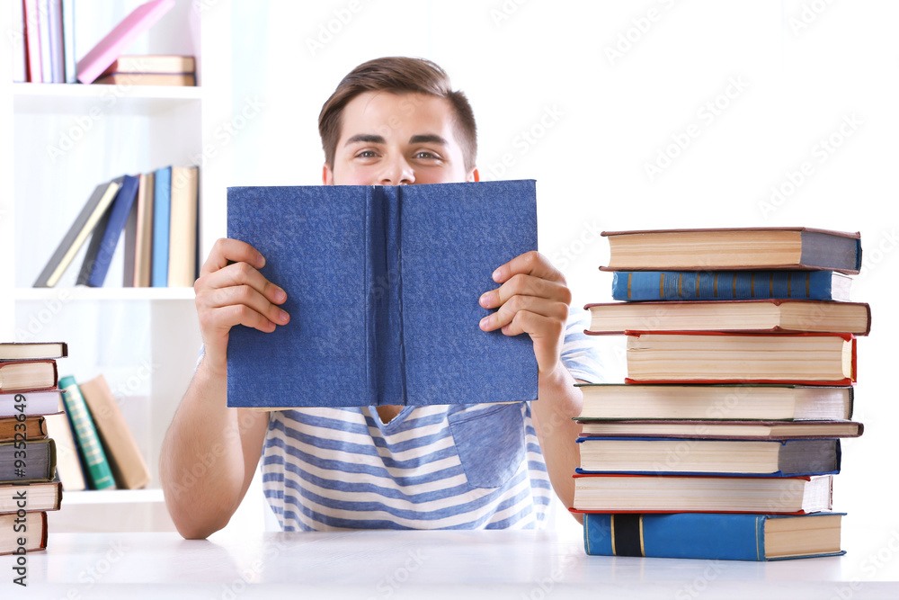 Young man reading book at table in room