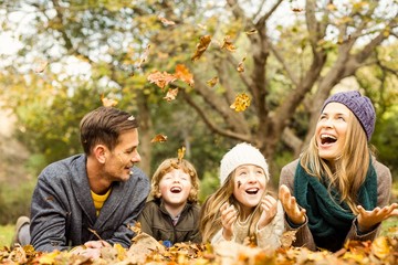 Smiling young family throwing leaves around