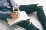 Fototapeta  - Woman on the bed with old book and cup of coffee, top view point