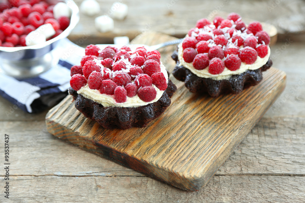 Sweet cakes with raspberries on wooden table background