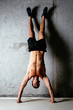 Photo of a sportsman doing a handstand against a concrete wall