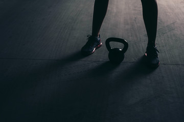 Wall Mural - Close-up of legs and a kettlebell lying on a concrete floor