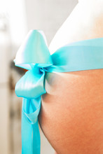 Belly Of A Pregnant Girl With A Blue Ribbon
