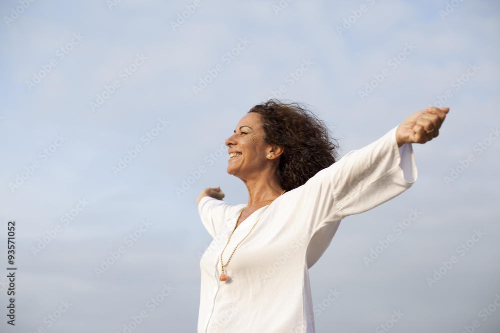Mujer madura feliz con los brazos abiertos al cielo - obrazy, fototapety, plakaty 