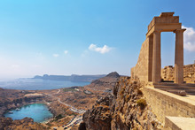 Greece. Rhodes. Acropolis Of Lindos. Doric Columns Of The Ancient Temple Of Athena Lindia The IV Century BC And The Bay Of St. Paul