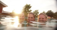 Portrait Of Three Girls Submerged In Swimming Pool At Sunset