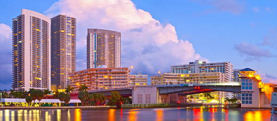 Wall Mural - Hallandale Beach Florida, modern buildings and colorful illuminated bridge at sunset