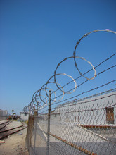 Barbed Wire Razor Fence With Blue Sky And Industrial Building