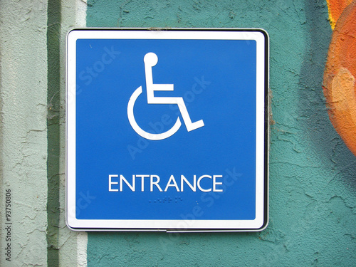 handicap entrance sign on painted stucco wall buy this stock photo