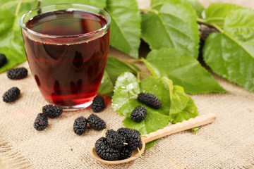 Wall Mural - Glass of refreshing mulberry juice with berries on table close up