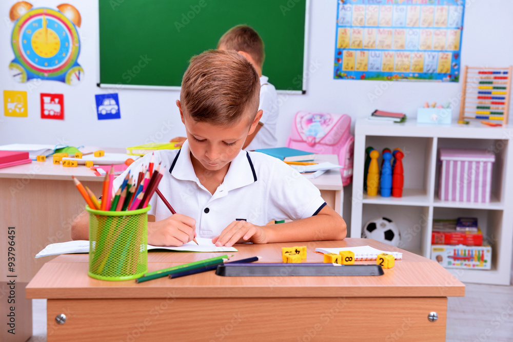 Little boy drawing at the desk in classroom