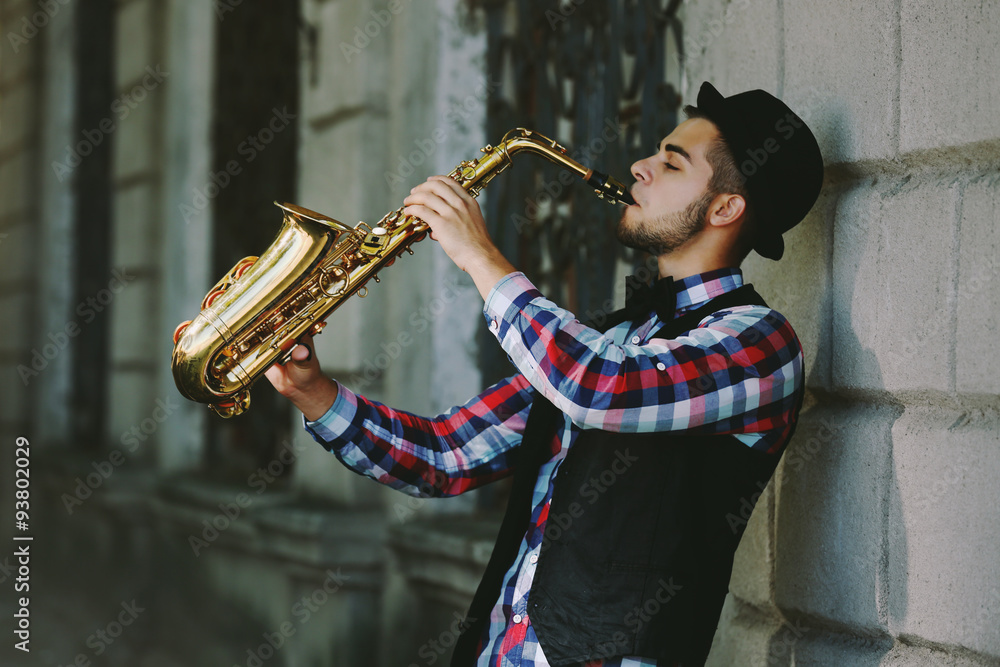 Man with saxophone outside near the brick wall