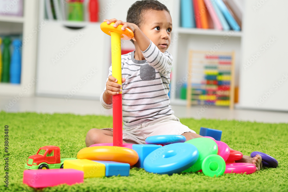 Little boy playing with his toys in the room