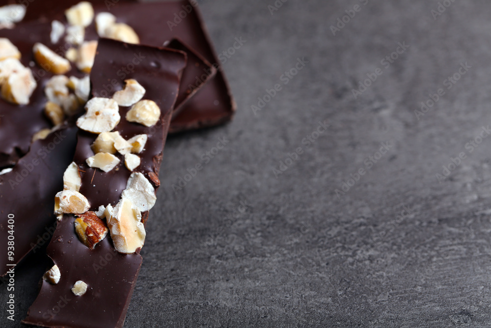 Black chocolate pieces and nuts on dark gray background