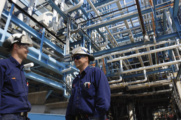 Wall Mural - oil and gas workers with giant pipelines in the background