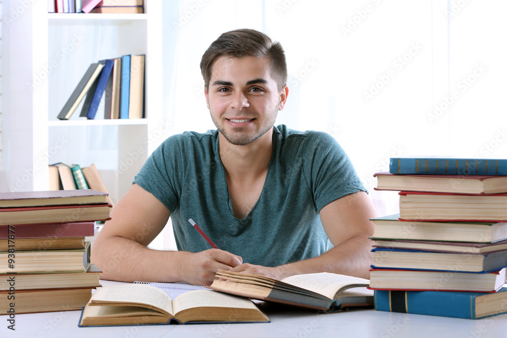 Young man reading book at table in room