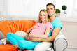 © Africa Studio - Young pregnant woman with husband on sofa in room