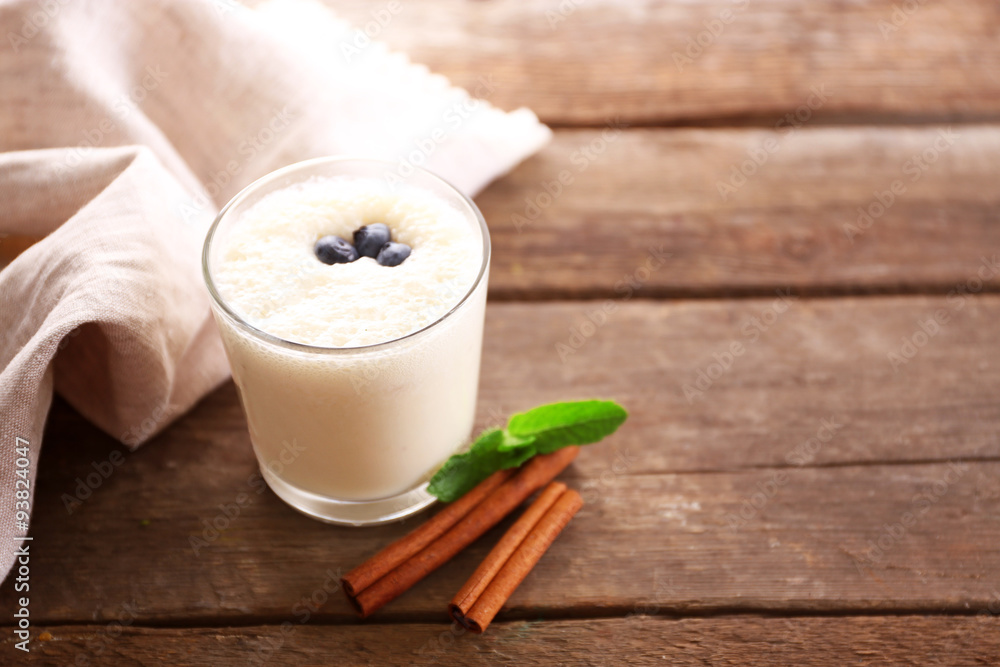 Fresh yogurt decorated with blueberries and cinnamon against wooden background